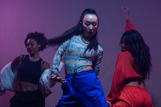 Danseuses en scène, Mathilde Delahaye au centre, entourée de deux autres artistes, dans une ambiance colorée et dynamique.